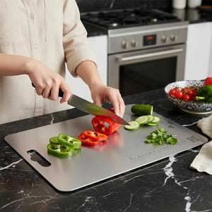 Person cutting vegetables on a stainless steel cutting board in a kitchen.