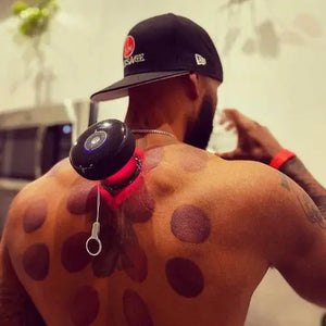 Person with a black cap and visible tattoos on their back, wearing a red band around their wrist.