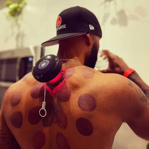 Person with a black cap and visible tattoos on their back, wearing a red band around their wrist.